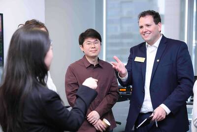 Zach Klonsinski (Undergraduate Admissions), in a navy suit with an ND pin, smiles and gestures, talking to Global China Scholars.